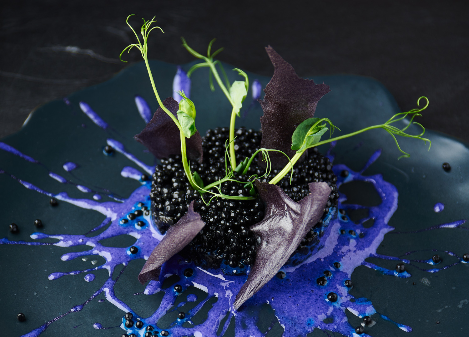 Risotto with cuttlefish ink and black caviar on a black background. Vertical shot.