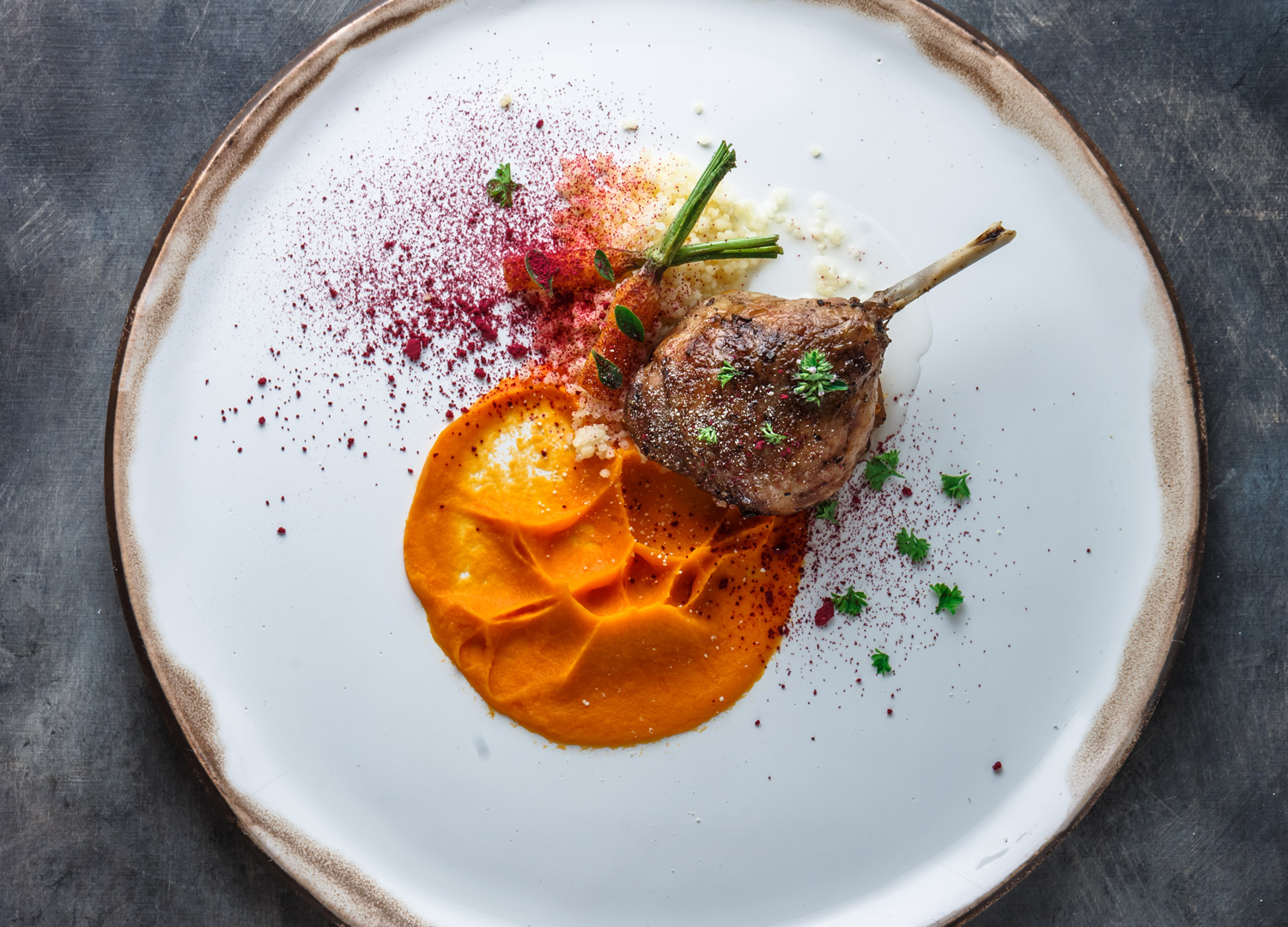 Duck leg confit with batat puree, carrots and couscous, restaurant meal, copy space.